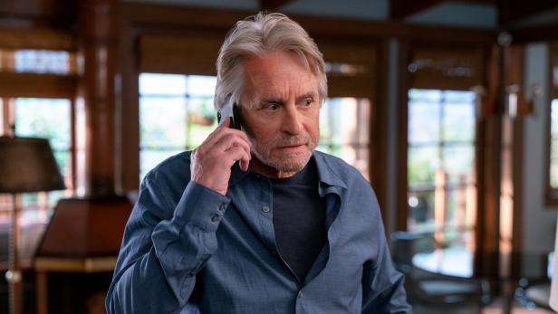 Michael Douglas telefoniert besorgt mit einem Smartphone.