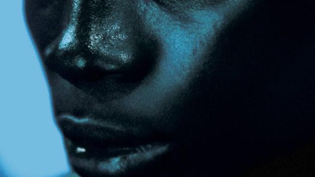 Das Filmplakat für „Sakawa“ zeigt das Gesicht einer dunkelhäutigen Person in blauem Licht.