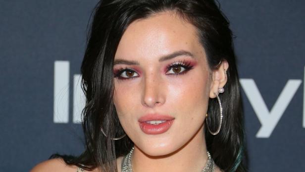 Bella Thorne trägt ein weißes Kleid und mehrere Halsketten.