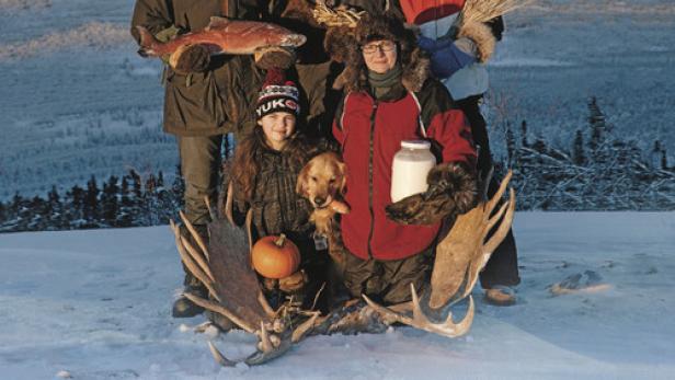 Das Filmplakat zu „First We Eat“ zeigt eine Familie in Winterkleidung in einer verschneiten Landschaft.