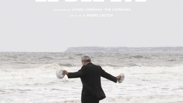 Ein Mann mit Hund läuft am Strand entlang, im Hintergrund das Filmplakat „Le Bel Été“.