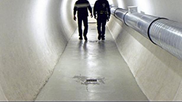 Zwei Arbeiter gehen in einem Tunnel des CERN entlang.