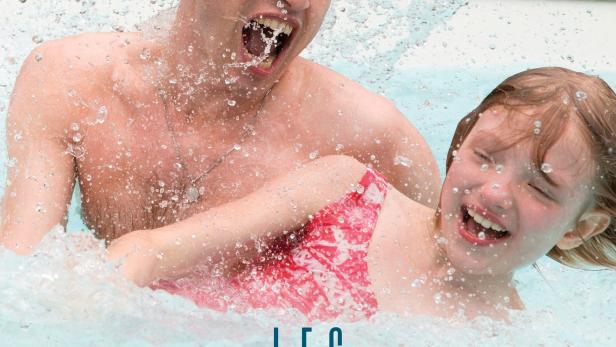 Ein Mann und ein Mädchen planschen lachend im Wasser.