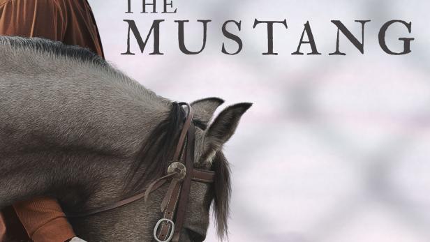 Ein Mann in brauner Kleidung steht neben einem Pferd; Filmposter für „The Mustang“.