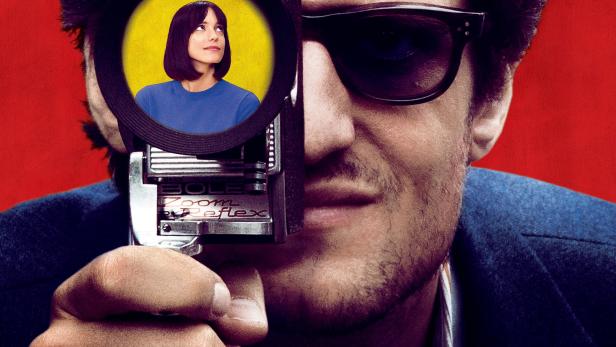 Das Filmplakat für „Le Redoutable“ zeigt einen Mann mit einer Filmkamera vor rotem Hintergrund.