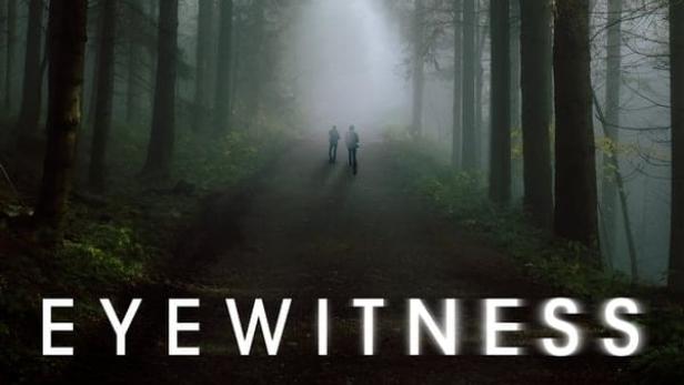 Zwei Personen gehen einen nebligen Weg entlang, gesäumt von hohen Bäumen. Im Vordergrund steht der Titel „Eyewitness“.