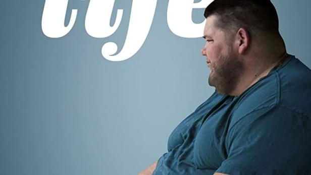 Ein Mann vor dem Hintergrund des Posters für die Fernsehsendung „My 600 lb Life“.