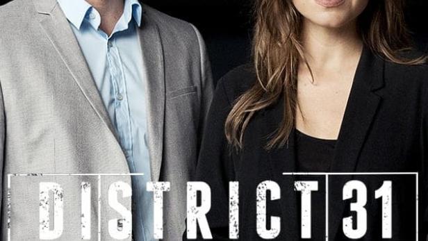 Ein Mann und eine Frau vor dem Logo der Fernsehserie „District 31“.