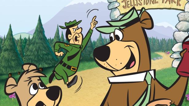 Yogi Bär und Boo Boo stehlen einen Picknickkorb, während ein Park Ranger sie verfolgt.