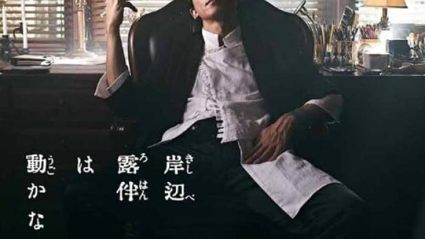 Ein Mann sitzt in einem Sessel und hält eine Zigarettenspitze in der Hand.