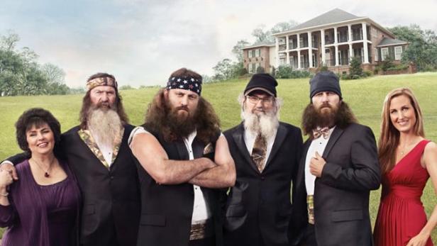 Das Ensemble der Fernsehserie „Duck Dynasty“ steht im Wasser vor einem Herrenhaus.