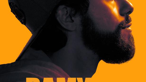 Porträt des Schauspielers Ramy Youssef vor orangefarbenem Hintergrund.