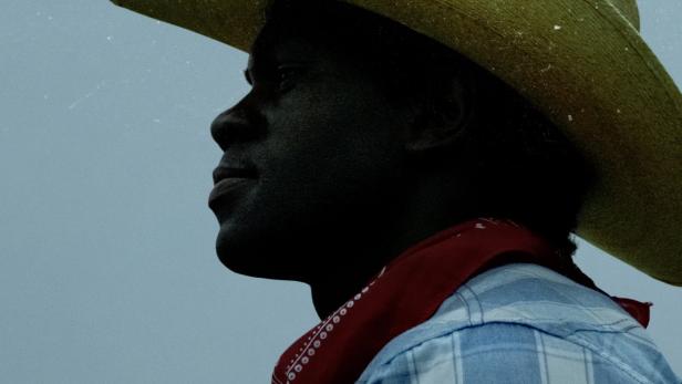 Ein Mann mit Cowboyhut und rotem Halstuch, im Hintergrund der Titel „Little America“.