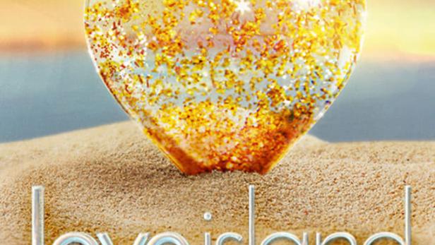 Ein glitzerndes Herz liegt im Sand vor einem Sonnenuntergang, darunter der Schriftzug „Love Island“.