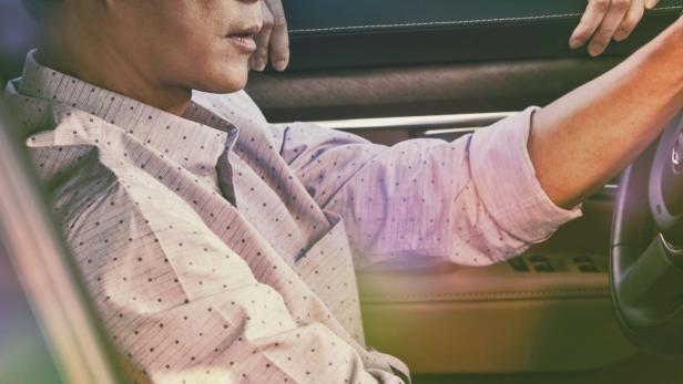 Ein Mann fährt Auto, während eine Frau aus dem Fenster schaut.