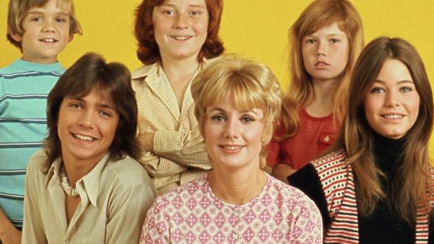 Das Ensemble der Fernsehserie „The Partridge Family“ posiert vor gelbem Hintergrund.