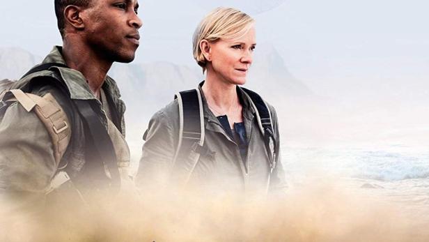 Das Filmplakat für „Outcasts“ zeigt zwei Personen vor einer Wüstenlandschaft mit einem abgestürzten Raumschiff.