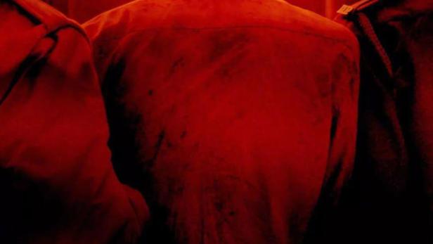 Ein Mann steht umringt von Polizisten im roten Licht, im Vordergrund der Titel „Delhi Crime“.