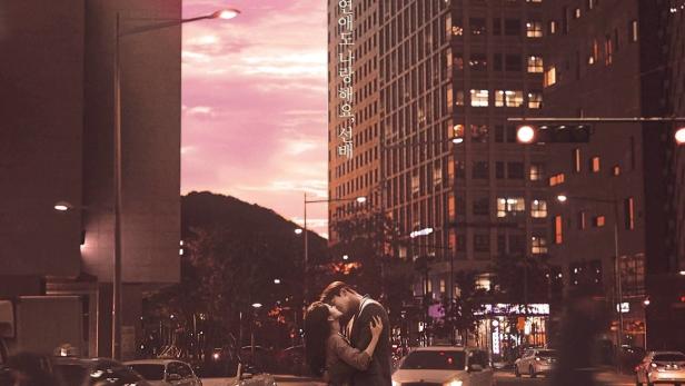 Ein Paar umarmt sich auf einem Zebrastreifen in einer belebten Stadt.