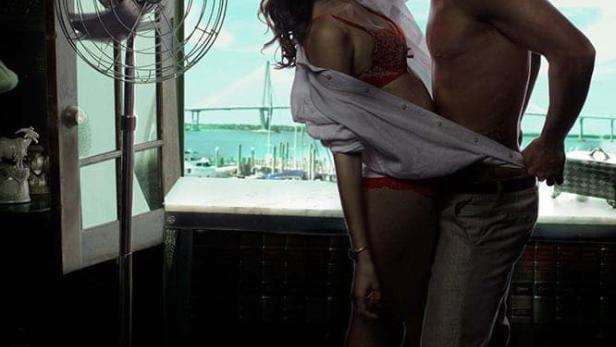 Ein Paar umarmt sich vor einem Fenster mit Blick auf das Meer, im Vordergrund der Titel „Reckless“.