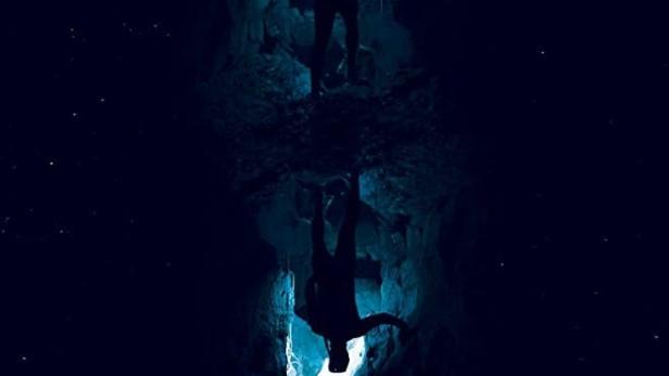 Ein Mann steht in einer Höhle, gespiegelt im Filmposter „The Most Unknown“.
