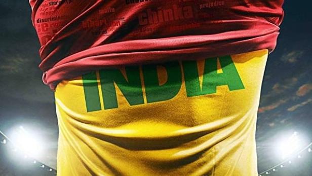 Ein Fußballspieler mit einem Trikot, das den Schriftzug „India“ und Begriffe wie „Rassismus“ zeigt.