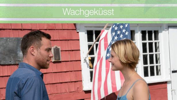 Ein Mann und eine Frau stehen vor einem Haus mit amerikanischer Flagge.