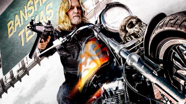 Ein Mann auf einem Motorrad hält eine Waffe vor einem Schild mit der Aufschrift „Banshee, Texas“.