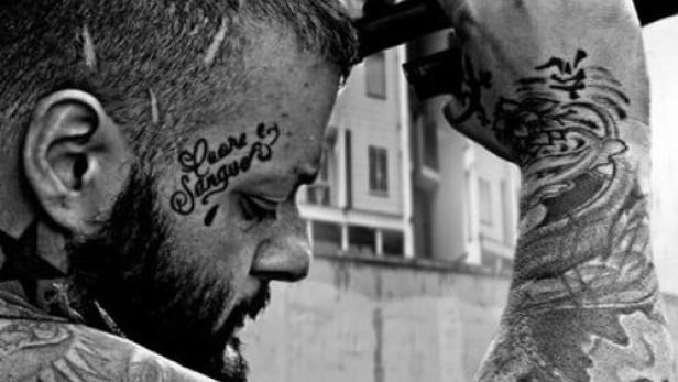 Ein Mann mit Tätowierungen hält eine Pistole an seinen Kopf; Filmposter für „Infidus“.