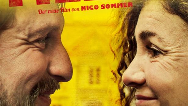 Das Filmplakat für „Familienfieber“ zeigt die Gesichter eines Mannes und einer Frau vor einem gelben Hintergrund.