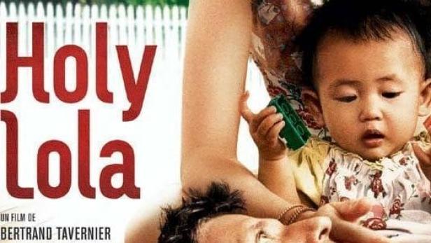 Das Filmplakat für „Holy Lola“ zeigt eine Frau, ein Baby und einen Mann vor einem asiatischen Gebäude.