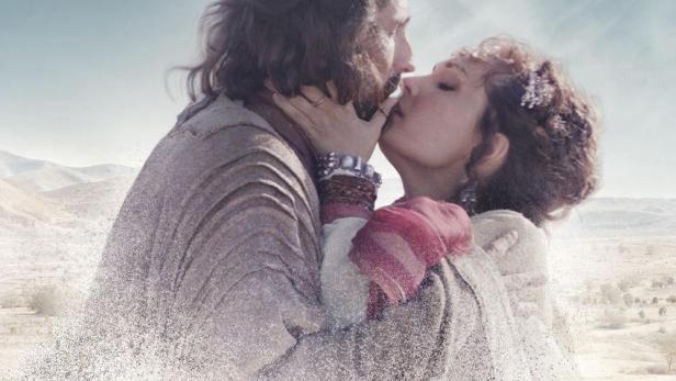 Ein Paar umarmt sich innig vor einer Wüstenlandschaft, im Stil des Filmplakats „Barabba“.