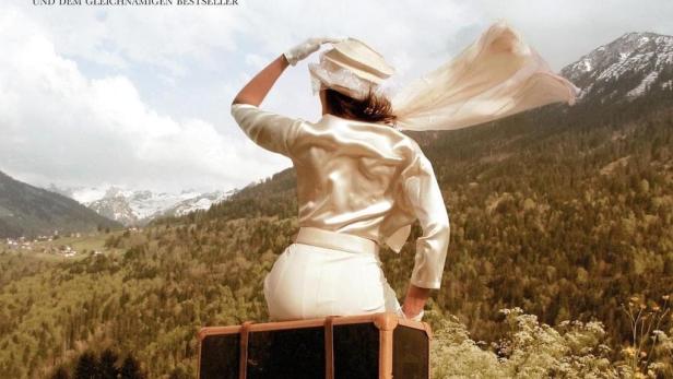 Das Filmplakat für „Der Atem des Himmels“ zeigt eine Frau auf einem Koffer vor Bergkulisse.