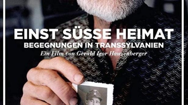 Ein älterer Mann hält ein Foto eines jungen Mannes in Uniform, vermutlich eine Szene aus dem Film „Einst süße Heimat“.