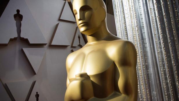 Eine goldene Oscar-Statue vor einem dekorativen Hintergrund.