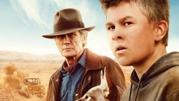 Das Filmplakat zu „Buckley's Chance“ zeigt einen Jungen, einen Mann mit Hut und einen Hund in der australischen Wüste.