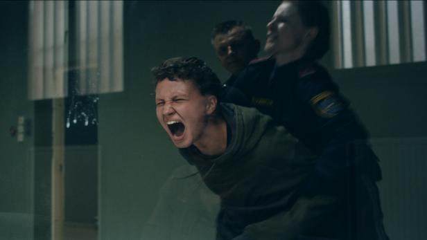 Eine junge Frau schreit, während sie von zwei Polizisten abgeführt wird.