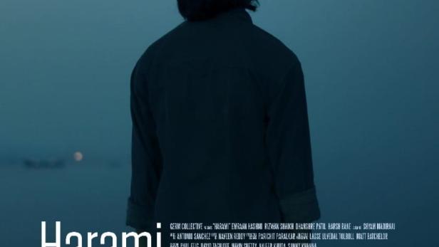 Ein Mann steht am Ufer, im Hintergrund das Filmplakat „Harami“.