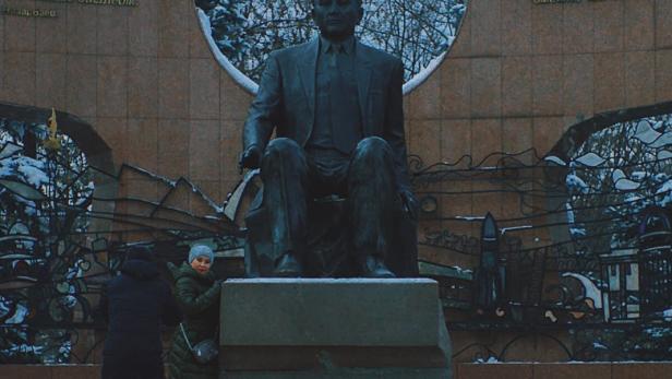Ein Filmplakat für „Welcome to the USA“ mit einer Statue und Personen im Vordergrund.