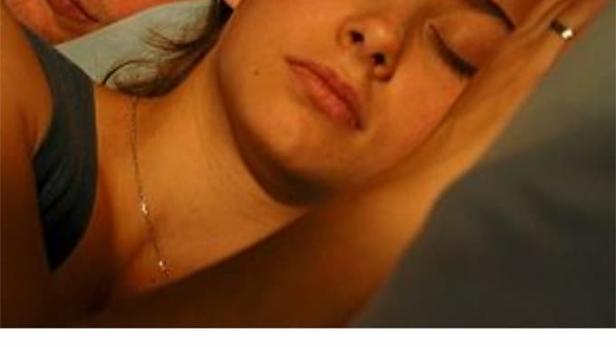 Ein Mann blickt aufmerksam, während eine Frau neben ihm schläft.