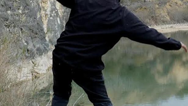 Ein Mann wirft Steine in einen See in einem Steinbruch.