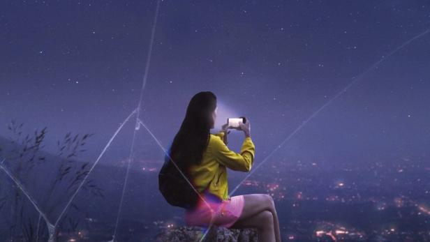 Plakat für den Film „Roamers“: Eine junge Frau fotografiert die nächtliche Stadt unter einem Sternenhimmel.