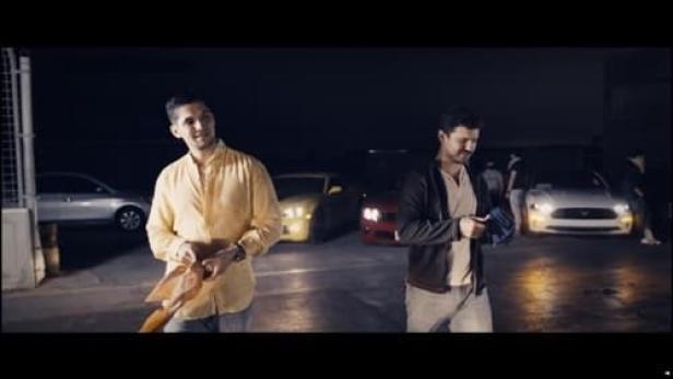 Zwei Männer stehen nachts vor mehreren Autos.