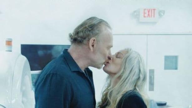 Ein Mann und eine Frau küssen sich vor dem Hintergrund des Filmplakats „Endlich unendlich“.