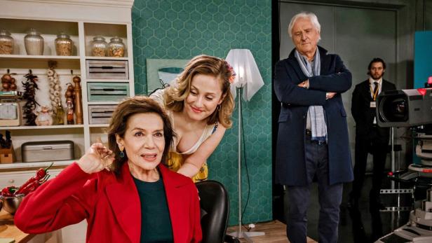 Drei Schauspieler und ein Kameramann stehen am Set einer Fernsehproduktion.