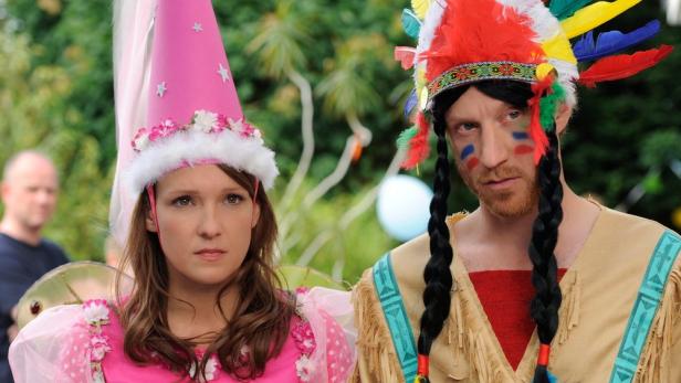 Eine Frau im rosa Feenkostüm und ein Mann als Indianer verkleidet stehen nebeneinander.