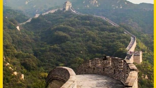 Ein Abschnitt der Chinesischen Mauer schlängelt sich über bewaldete Hügel.