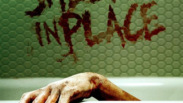 Eine blutverschmierte Hand hängt über dem Rand einer Badewanne; an der Wand steht „Shelter in Place“.