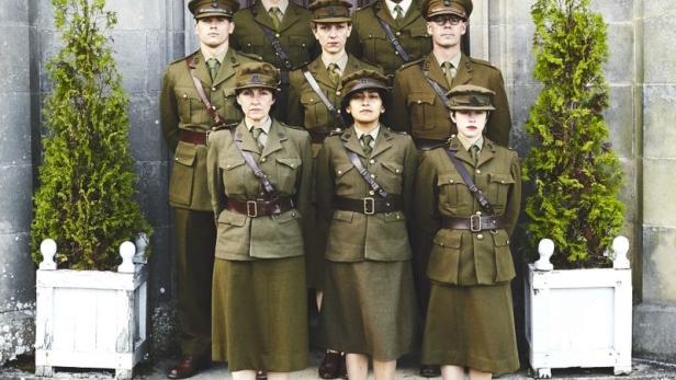 Eine Gruppe von Männern und Frauen in Uniformen posiert vor einer Tür.