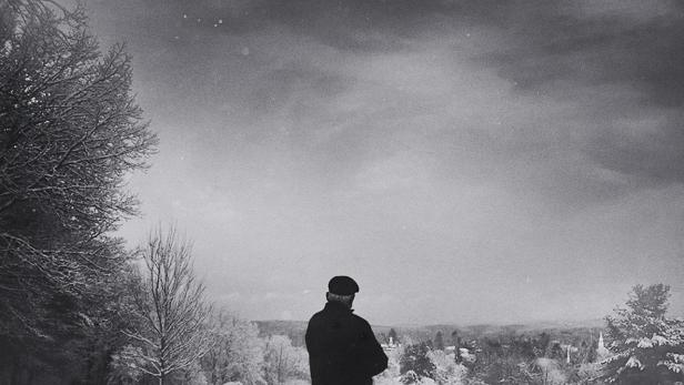 Ein Mann steht im Winter vor einer Bank mit Blick auf Dunblane.